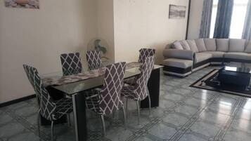 A dining area with a table and chairs, a sofa, and a fan.