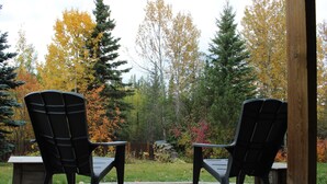 Zwei schwarze Adirondack-Stühle vor einer Holzterrasse mit einem Backsteinweg.