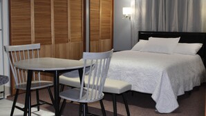 Ein Hotelzimmer mit einem Bett, einem Tisch mit zwei Stühlen und einem Holzschrank.