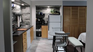 Eine kleine Küche mit Essbereich, Holzschränken, einem Kühlschrank und einer Pflanze.