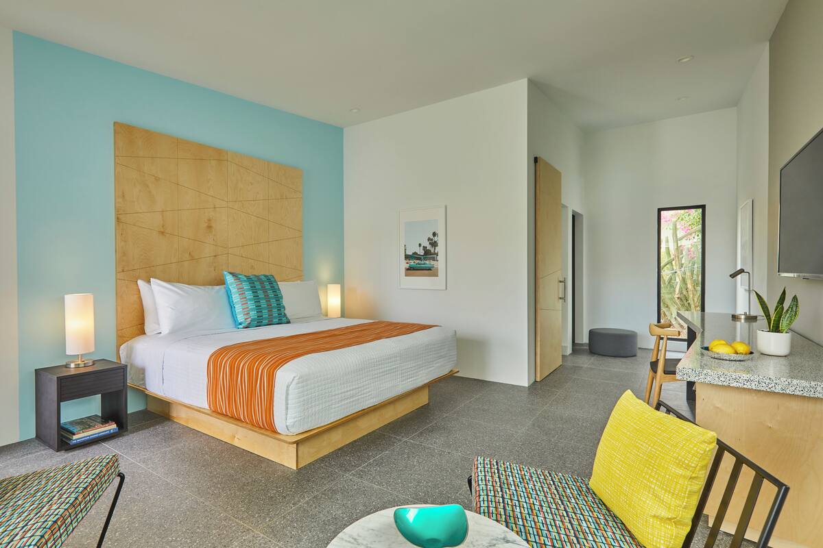 Een moderne hotelkamer met een groot bed, nachtkastjes, een bureau en een stoel.