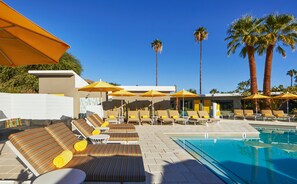 Ein Poolbereich mit Liegestühlen, Sonnenschirmen und Palmen.