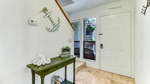 A hallway with a green table, a white door, and a staircase. - Sea Glass Cove - Hosted By Moore AI Rentals (Fernandina Beach)