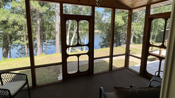 Une véranda couverte donnant sur un lac et des arbres.