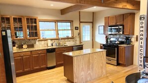 A modern kitchen with wooden cabinets, a granite countertop, and a central island. - Family Lake Getaway on Davis Stream  5BR + Kayaks (Jefferson)