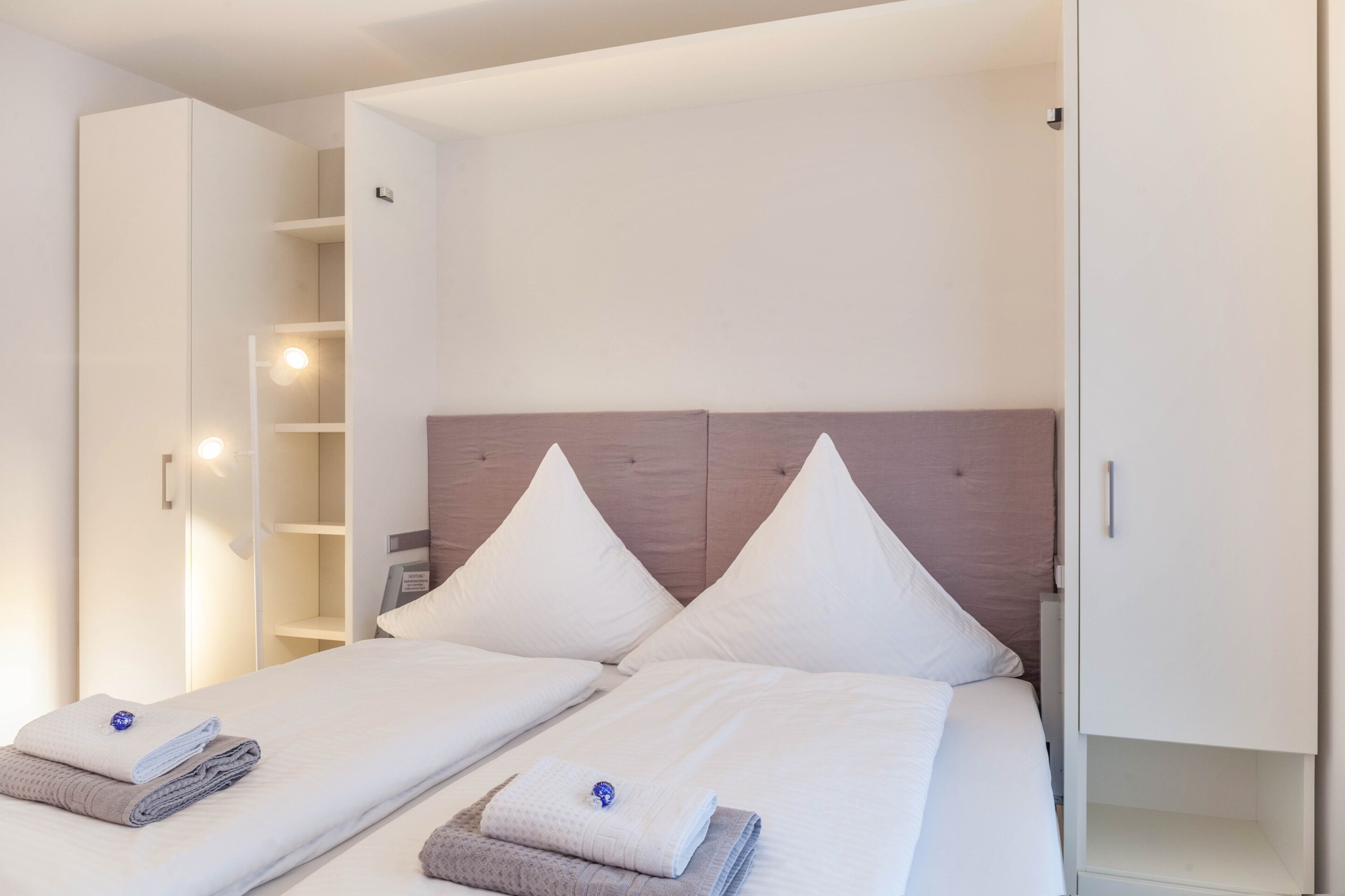 Un dormitorio con dos camas, un armario y una estantería.