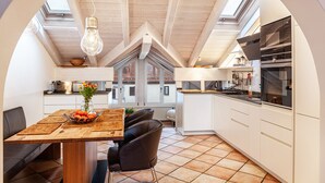 Een moderne keuken met witte kasten, een eethoek met een houten tafel en een dakraam.