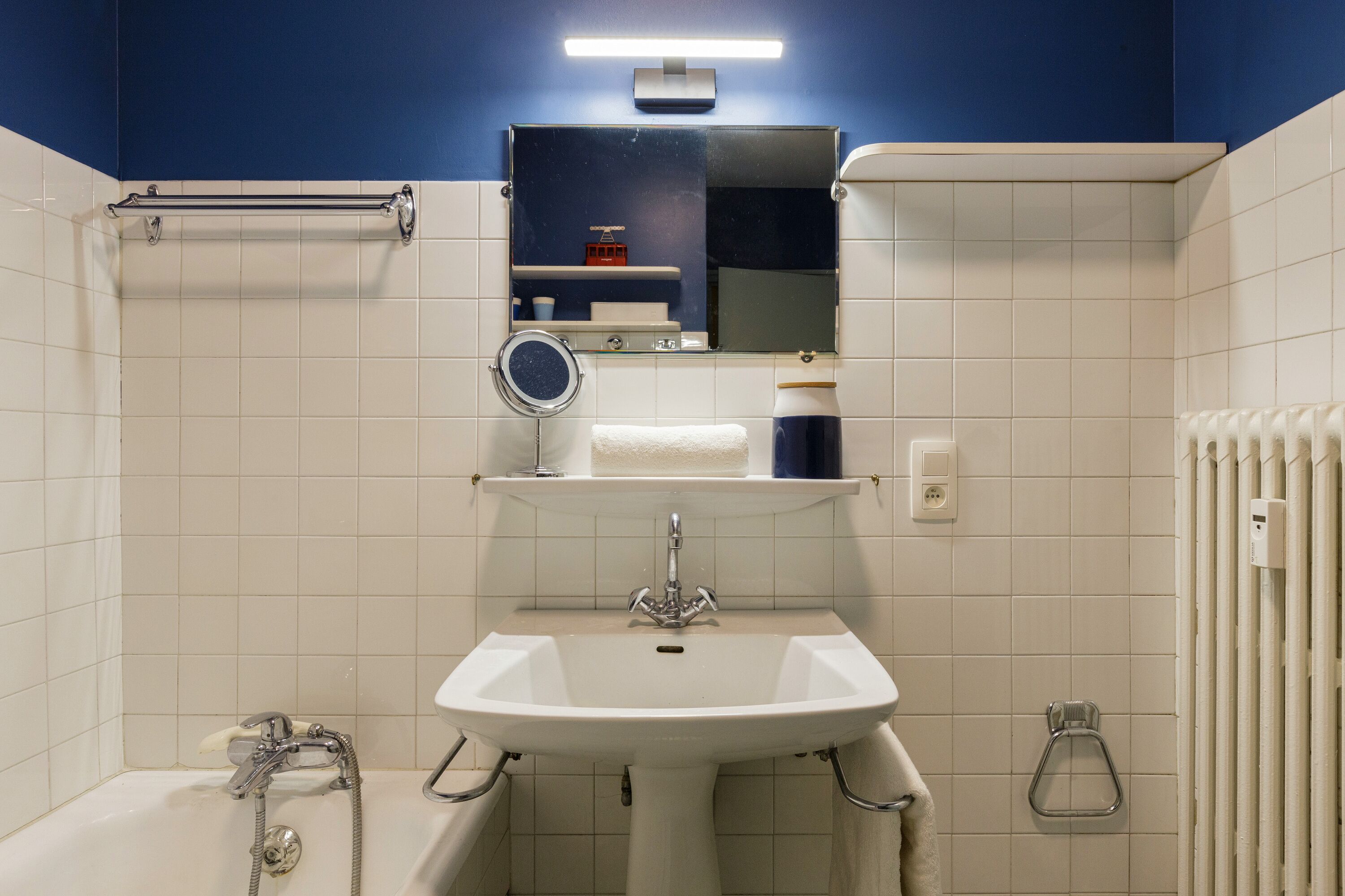 A bathroom with a white sink, a mirror, a towel rack, and a shower.