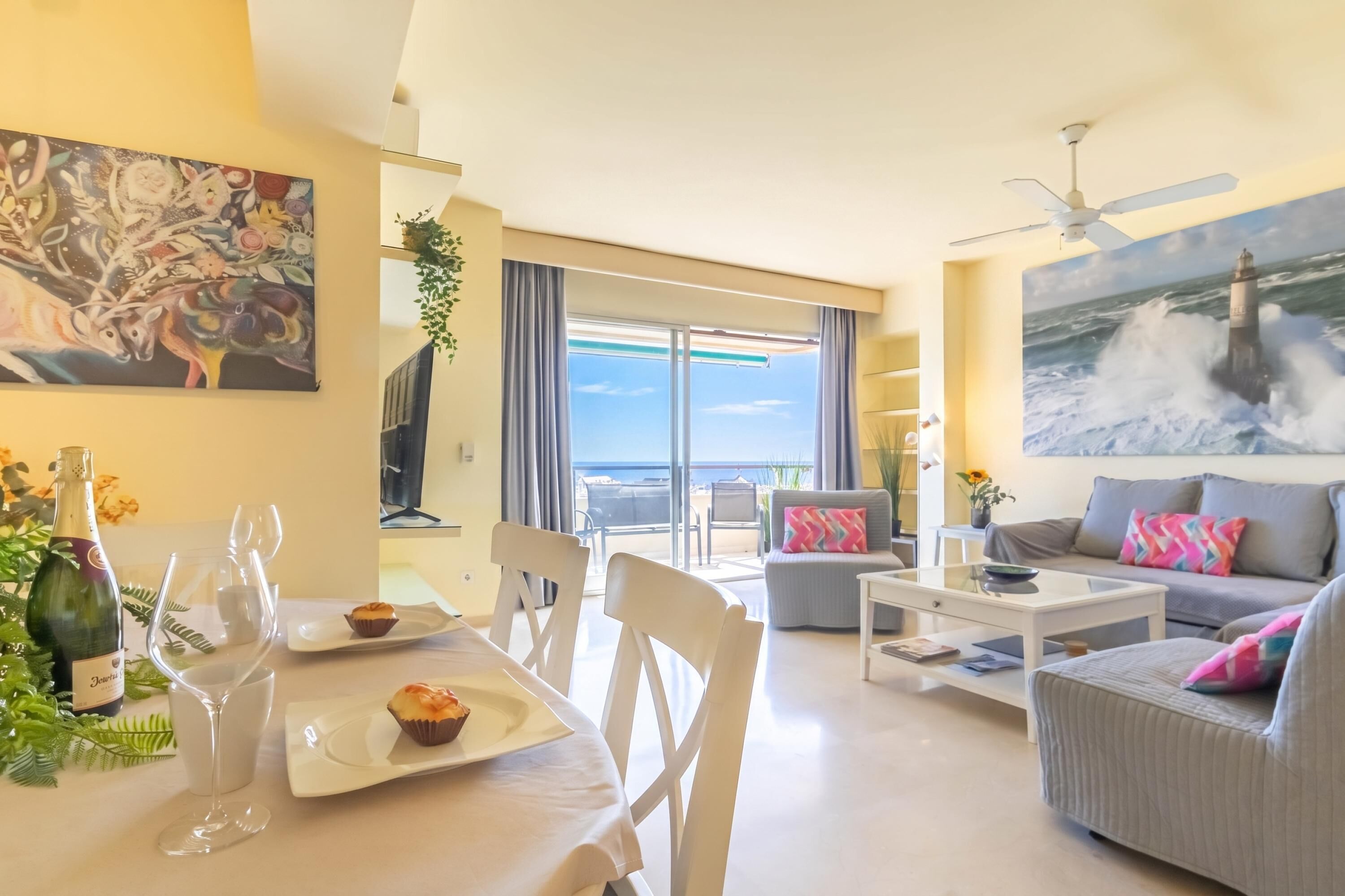 Ein modernes Wohnzimmer mit Essbereich, ein Balkon mit Meerblick und einem Bild an der Wand.
