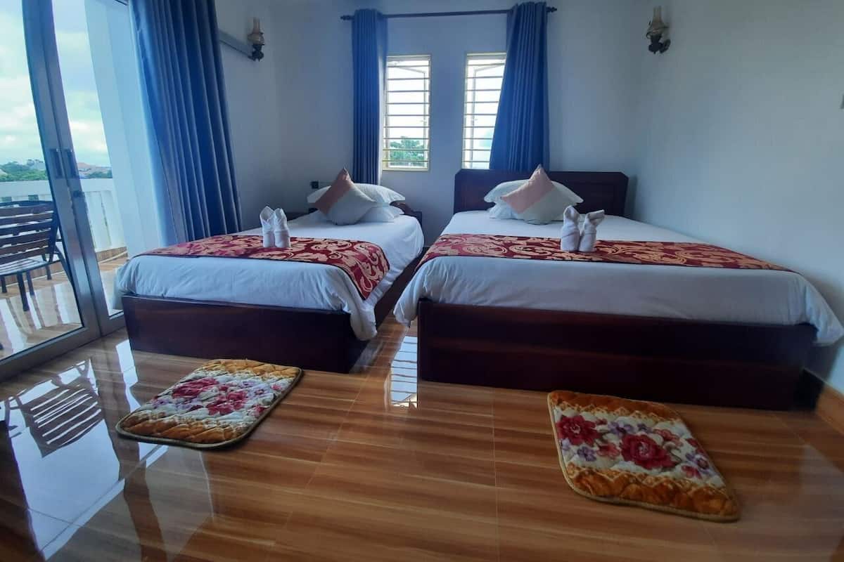 A hotel room with two beds, a balcony, and a large window with curtains.