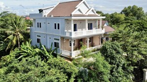 A two-story house with a balcony, surrounded by lush greenery. - Realkhom Villa (Siem Reap)