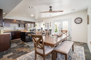 Een moderne keuken met donkere houten kastjes, een centraal eiland en een eetgedeelte met een houten tafel en stoelen.
