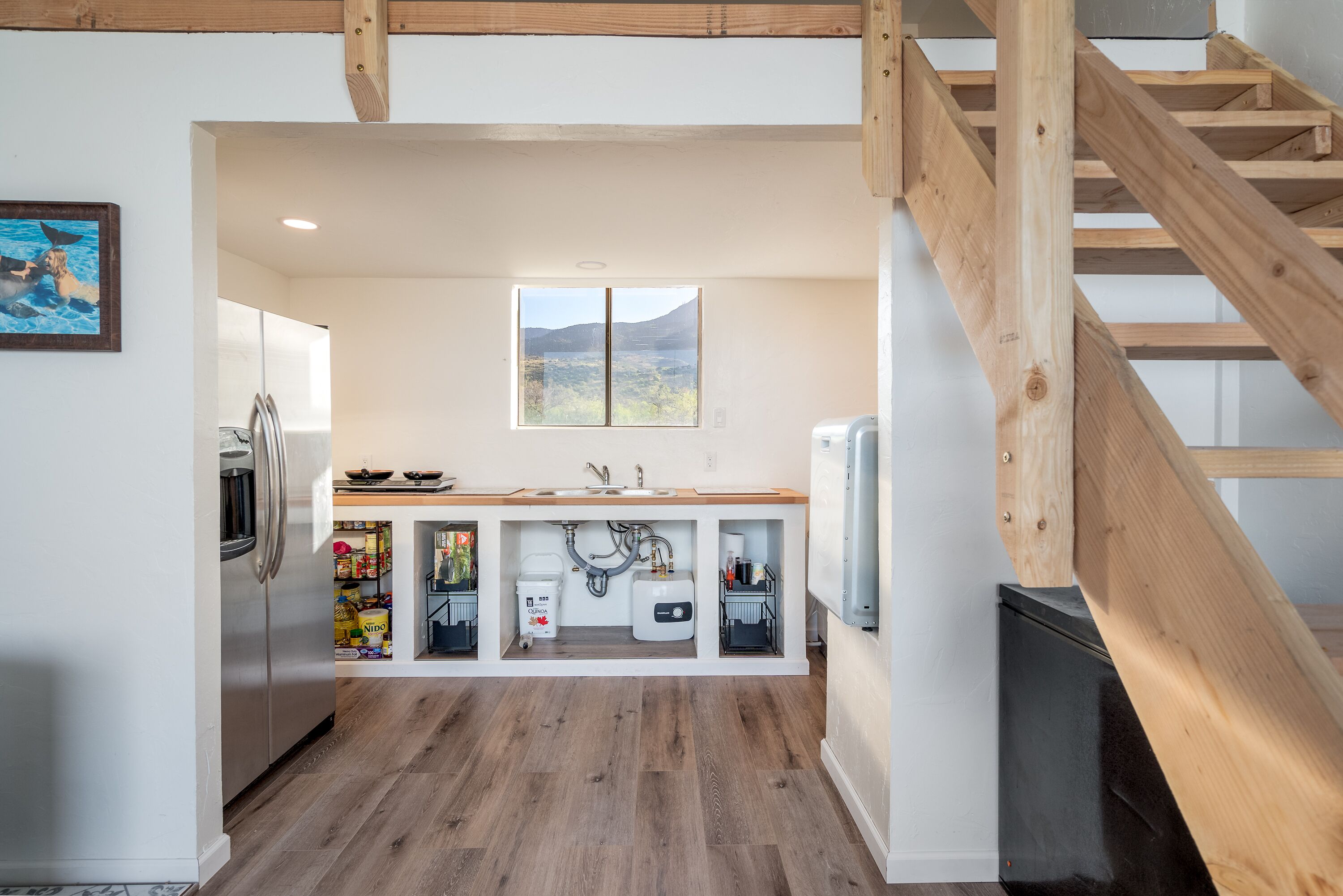 A modern kitchen with wooden beams, a built-in sink, and a window overlooking a mountainous landscape.