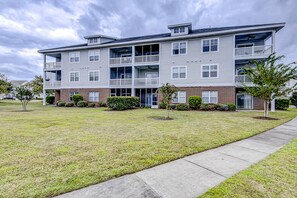 Ein mehrstöckiges Apartmenthaus mit Backsteinfassade und weißem Außenputz, mit Balkonen in jeder Etage.