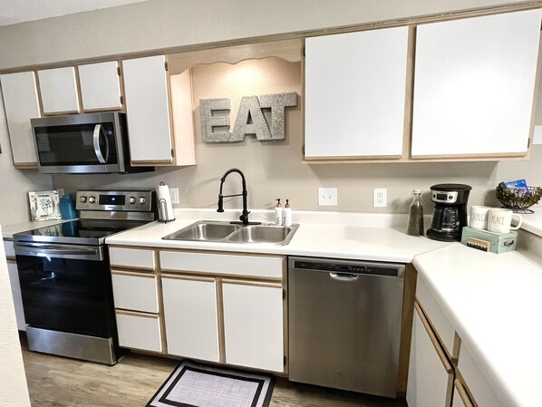 A modern kitchen with stainless steel appliances, a double sink, and a dishwasher.