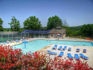 A swimming pool with lounge chairs and a covered area with solar panels.