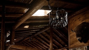 A rustic log cabin interior with a leather sofa, a stone fireplace, and a mounted buffalo head.