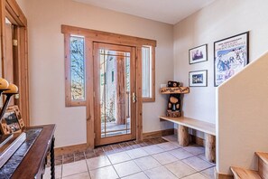 A wooden door with glass panels, a bench, and framed pictures on the wall.