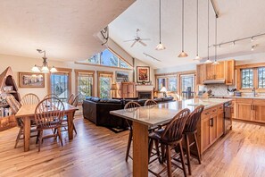 A spacious kitchen with wooden cabinets, a large island, and a dining area with chairs.
