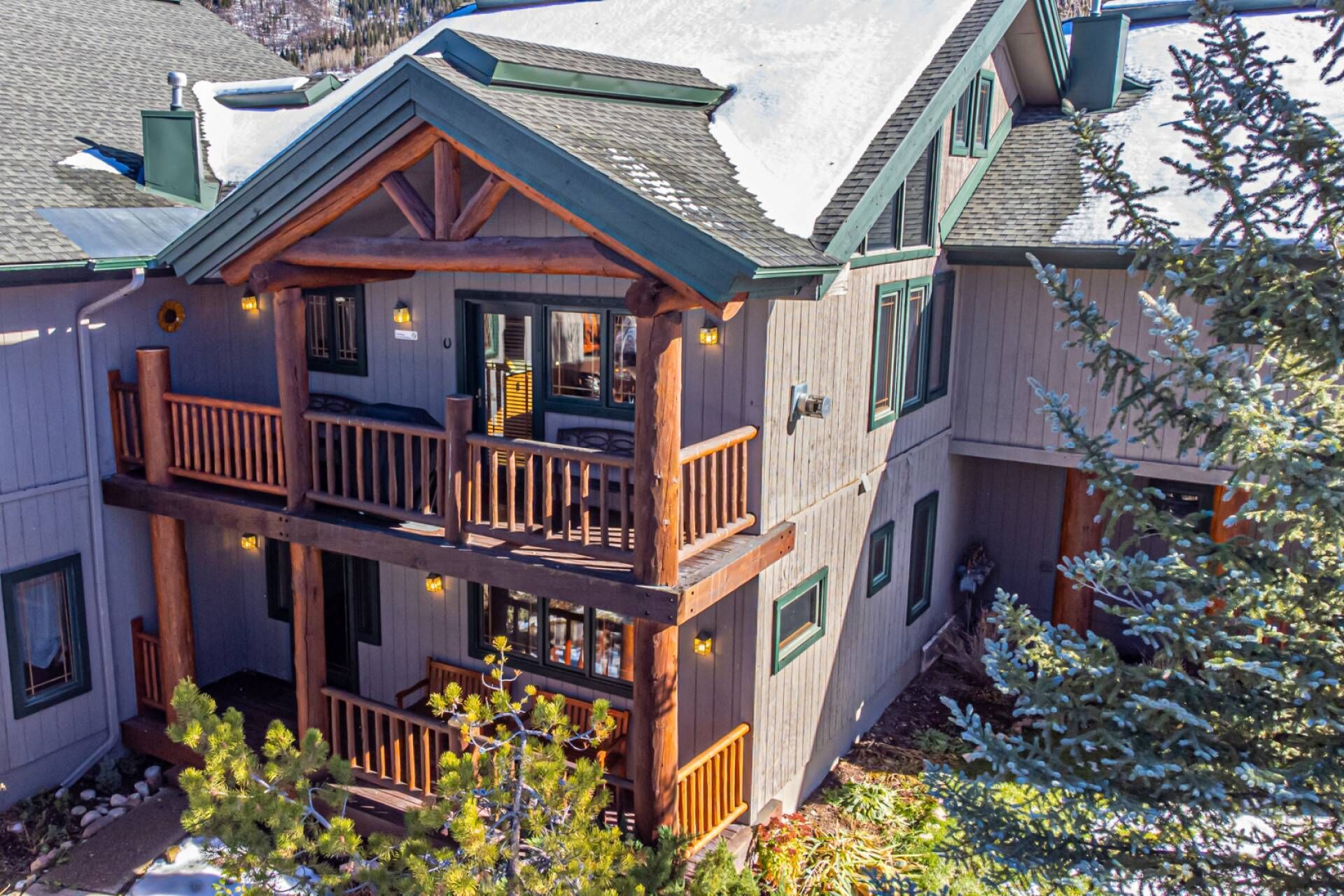 A two-story log cabin with a balcony, wooden railings, and a porch.