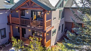 A two-story log cabin with a balcony, wooden railings, and a porch.
