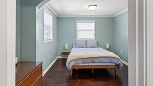 A bedroom with a bed, bedside tables, and a ceiling light fixture.