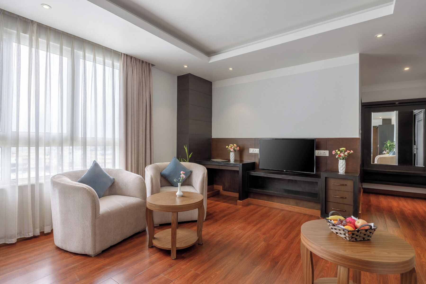 A modern living room with a sofa, a coffee table, a TV, and a fruit basket.