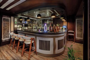 Zona de bar con mostrador curvo, taburetes de madera y luminarias colgantes.