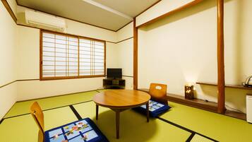 Una habitación japonesa tradicional con suelo de tatami, una mesa baja de tatami, un televisor y un biombio shoji.