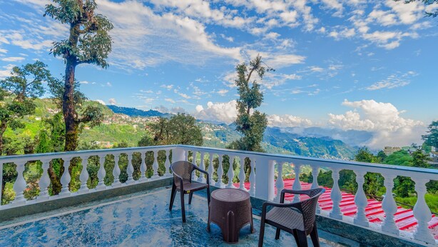 A balcony with a white balustrade, two wicker chairs, and a small round table. - The Junglee Bakri (Mussoorie)