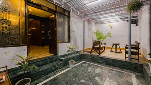 A lobby with marble flooring, a reception desk, and a seating area with chairs and tables. - The Junglee Bakri (Mussoorie)