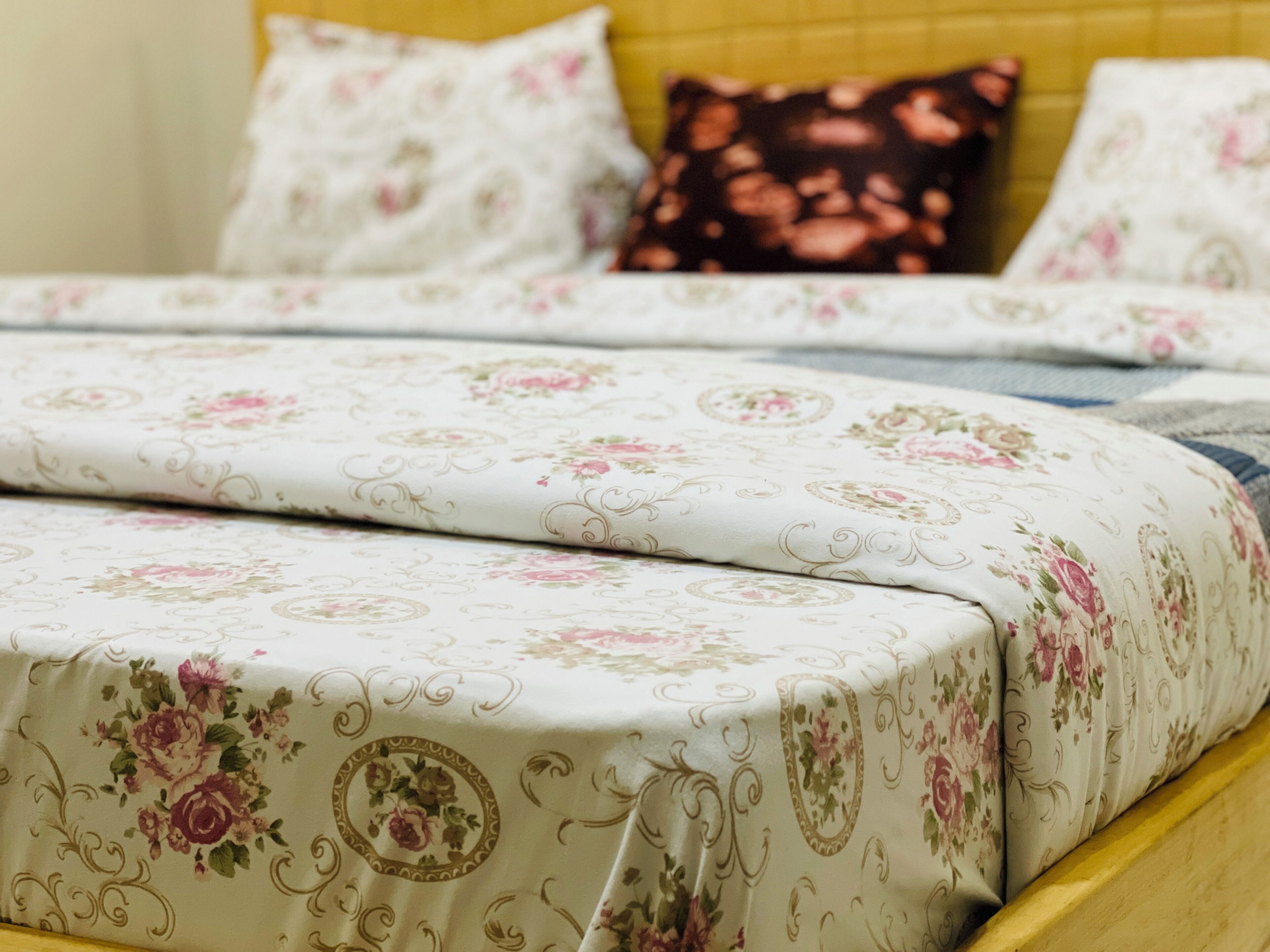 A bed with floral bedding and a wooden headboard.