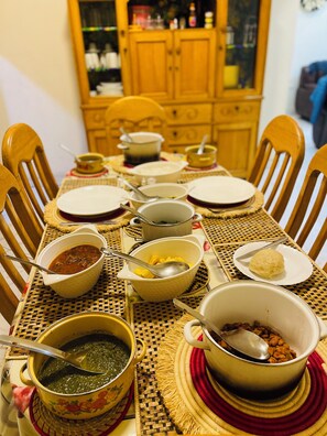 A dining table set with various dishes and utensils, surrounded by wooden chairs. - Nice Rooms, Unbeatable Prices (Ruhengeri)