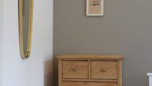 Quarto com cômoda de madeira, espelho e quadro pendurado na parede.