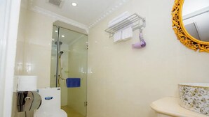 A bathroom with a toilet, a glass shower enclosure, a towel rack with towels, and a decorative mirror. - Cristina Boutique Hotel (Hanoi)