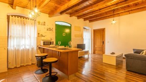 Un espace de vie compact comprenant un coin cuisine, un plancher en bois, un mur d’accent vert et un tabouret de bar.