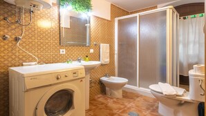 Une salle de bain équipée d’un lave-linge, d’un lavabo, d’un bidet et de toilettes.