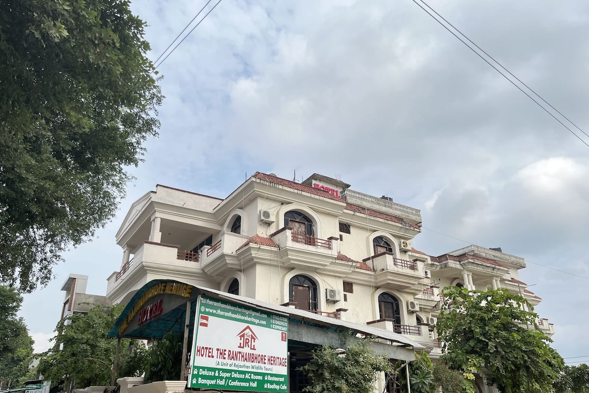 Een meerlaags gebouw met een bordje waarop 'Hotel The Ranthambhore Heritage' staat.