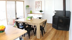 Un comedor con una mesa de madera, sillas negras, un armario blanco y una chimenea negra.