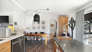 A modern kitchen with a wooden dining table, stainless steel appliances, and a cactus decoration. - JT Starry Night Getaway Pet-Friendly (Joshua Tree)