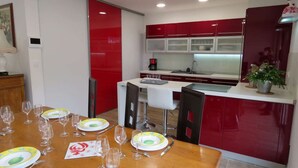 Una cocina moderna con gabinetes rojos, encimera blanca y un comedor dispuesto con platos y vasos.