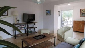Una sala de estar con sofá, una mesa de centro, un televisor sobre un mueble bajo y un aparador.