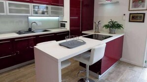 Una cocina moderna con armarios rojos, encimera blanca y una isla central con pileta.