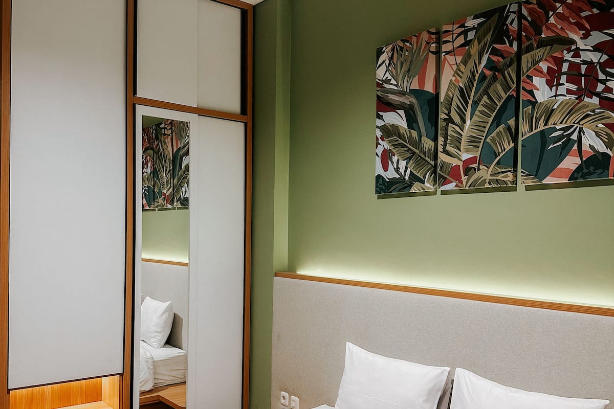 Una habitación de hotel con una cama, un armario y un cuadro abstracto grande en la pared.