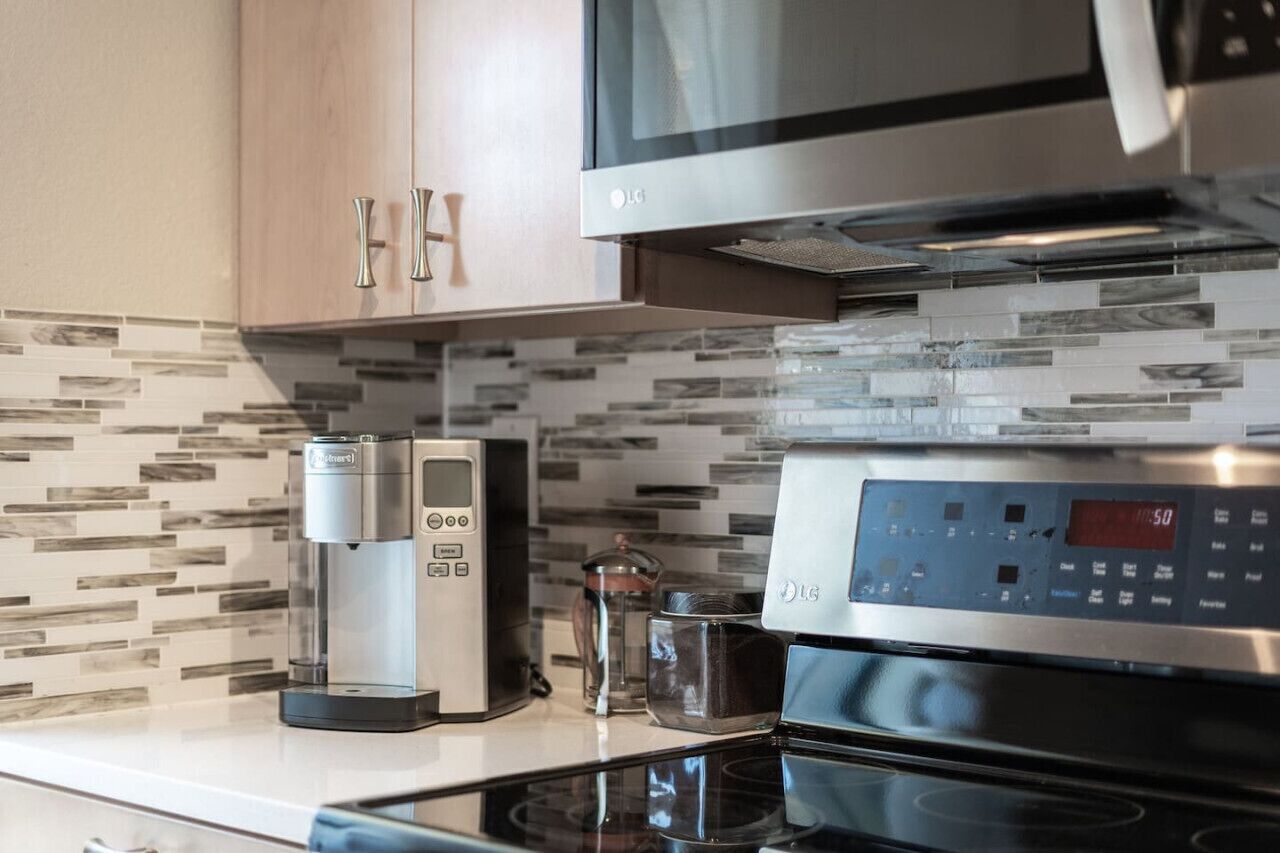 A modern kitchen with a coffee maker, a microwave, and a digital oven control panel.