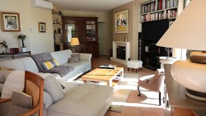 Una sala de estar con sofá, sillones, una mesa de centro, chimenea y estantería.
