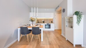 Eine moderne Küche mit Essbereich, Holzboden, weißen Schränken und einem eingebauten Backofen.