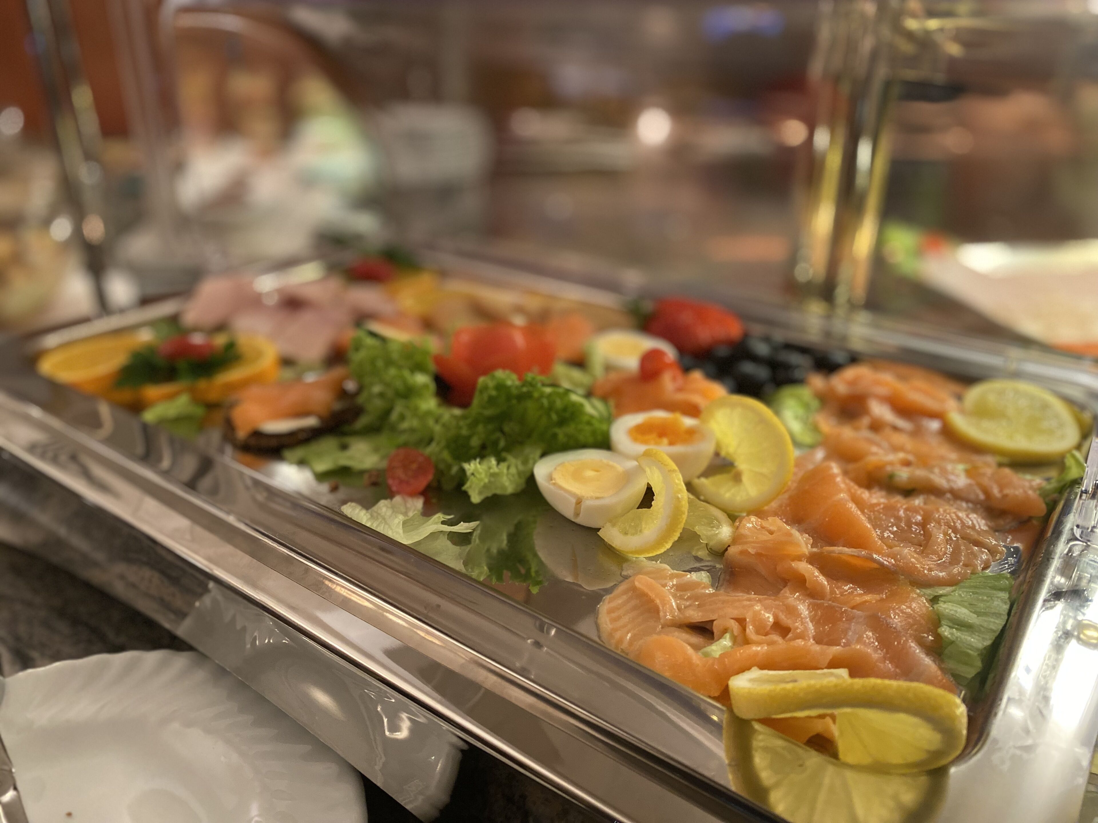 A buffet with various food items including salmon, eggs, and vegetables.