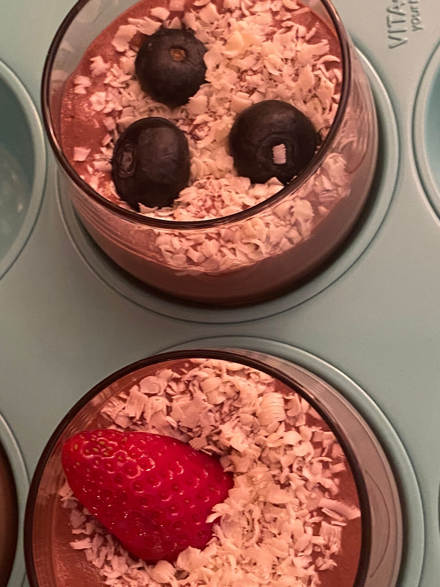 A dessert with chocolate mousse, blueberries, and a strawberry on a plate.
