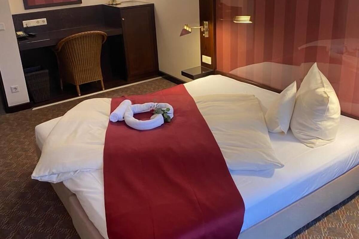 Une chambre d’hôtel avec un lit, un bureau, une chaise et un miroir.